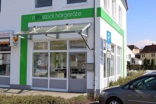 Modernes Fachgeschäft für Hörgeräte mit grüner Beschriftung an einer Straßenecke.